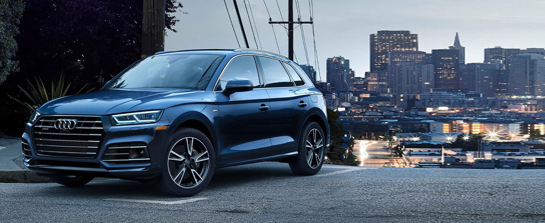 side frontal view of blue Audi Q5 vehicle cruising in the city at dusk