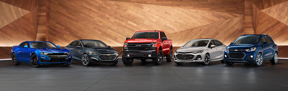 chevrolet multi color vehicle line up parked against a wood wall and concrete floor