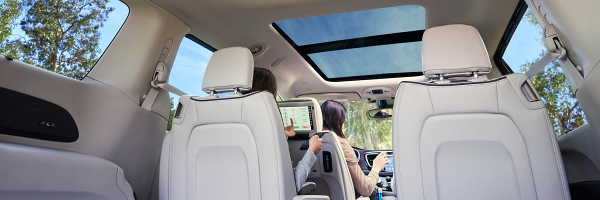 An interior view of the second row of a 2020 Chrysler Pacifica focusing on the Uconnect Theater.