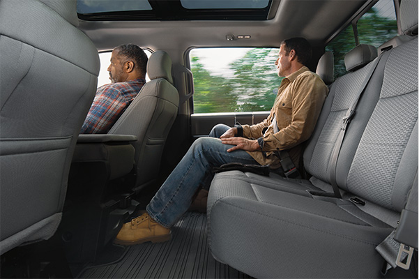 interior rear view of the Ford F-150 pickup truck with one person sitting in the back seat showcasing the large legroom