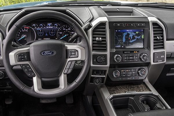 Interior view showcasing the dashboard featuring steering wheel, A/C controls, cup holders digital screen with navigation tools