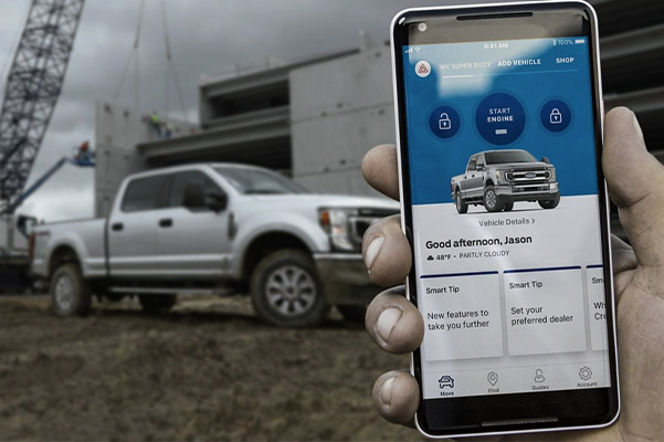 Hand holding smartphone on a job site with 2020 Ford Super Duty in the background