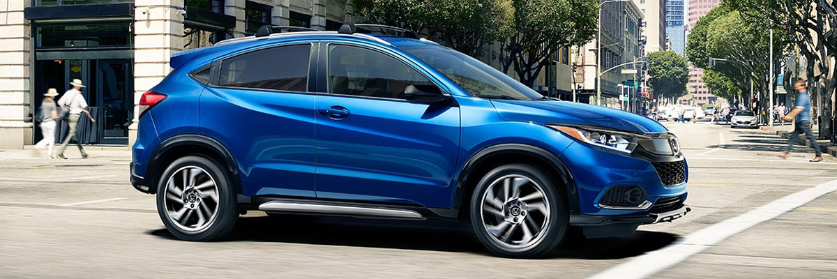 Image of a 2020 Honda HR-V Sport in Aegean Blue Metallic with alloy wheels driving down a city street
