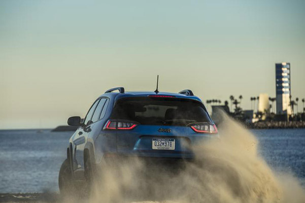 blue cherokee vehicle driving at a high speed and leaving dust behind