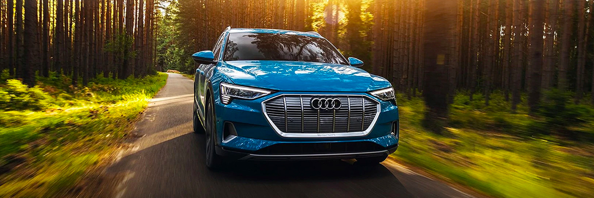 Front profile of the Audi e-tron® driving on the road.