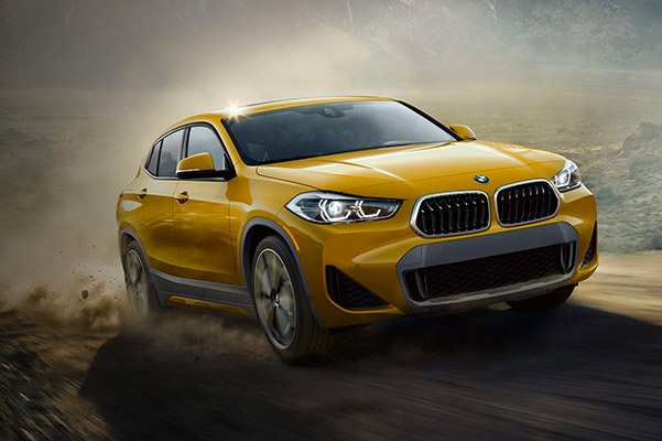 The BMW X2 in Galvanic Gold Metallic drives on a rugged dirt road