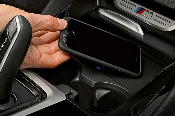 close up of hand placing smartphone on the wireless charger featured on the BMW X4 Sav