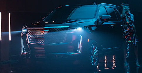 frontal profile view of 2021 cadillac escalade suv on a dark studio background with headlights on 