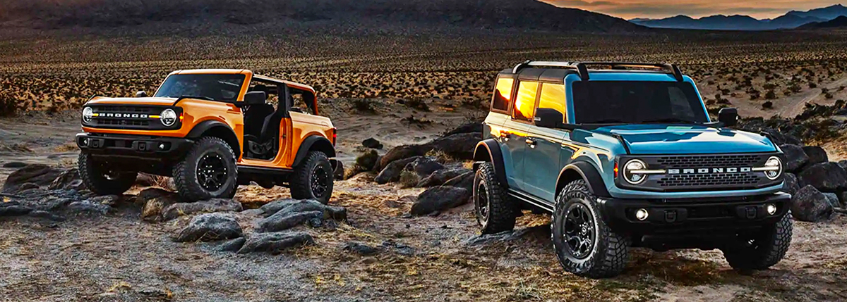 Various 2021 Ford Bronco models parked near each other in the desert at sunset