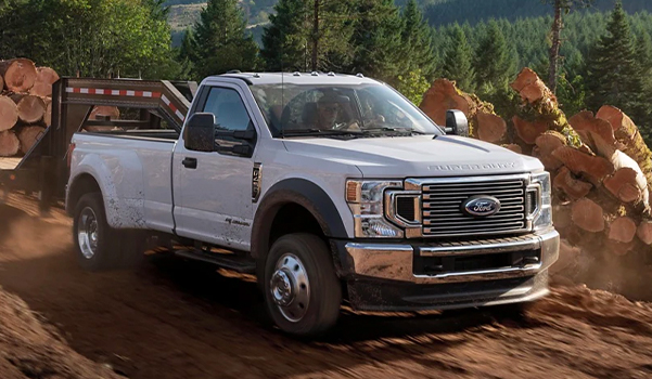 2021 Ford F-450 Super Duty XL STX in Oxford White hauling logs on dirt path near forest