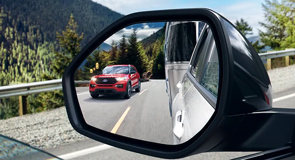 Close up of an auto dimming sideview mirror showing the reflection of a 2021 Ford Explorer in Lucid Red
