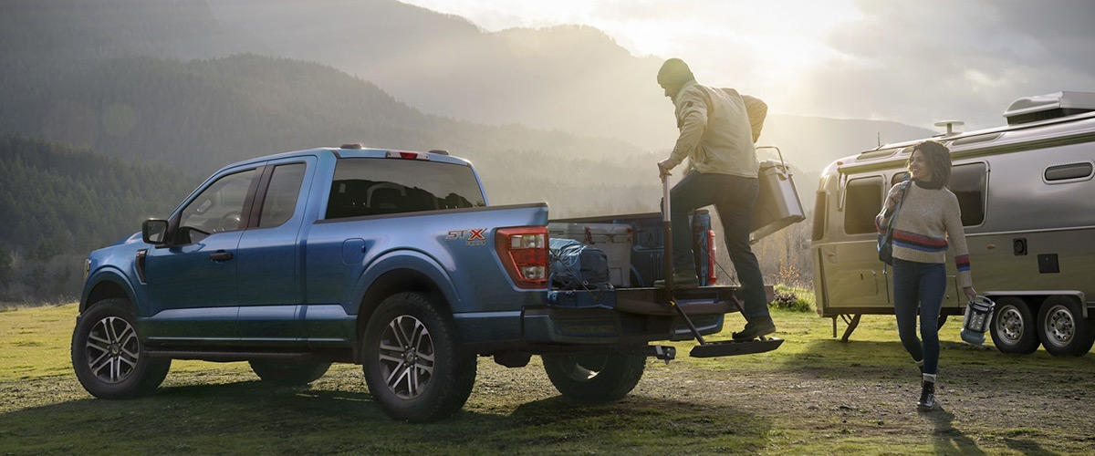 ford f-150 parked in the grass being unloaded for a camping trip