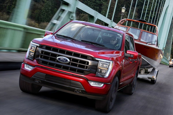 New 2021 Red ford f-150 driving towing a boat