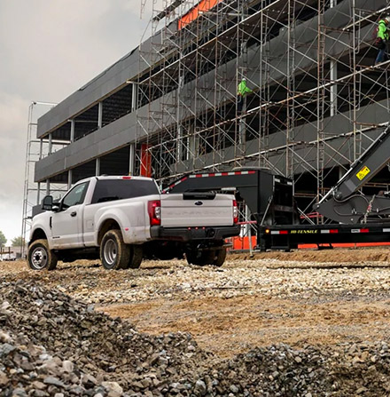 Rear view of 2021 Ford Super Duty on a large scale building job towing a backhoe