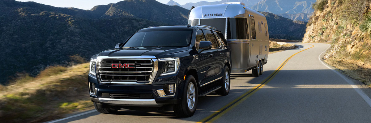 2021 GMC Yukon Towing Airstream Camper in front of Mountain Range