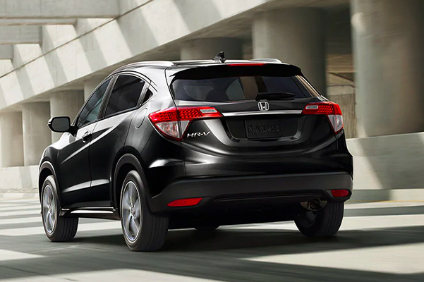Rear driver-side view of the 2021 Honda HR-V EX-L in Crystal Black Pearl driving on a highway.