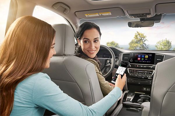 2021 Honda Pilot interior shown in gray leather with daughter showing mother how to connect her smart phone to the car