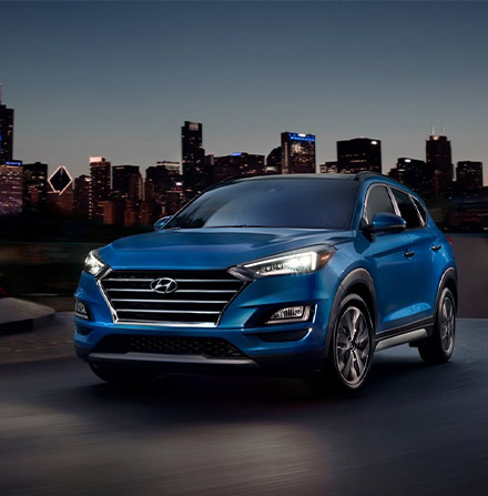 blue 2021 Tucson with LED Headlights on at night time on a city scene