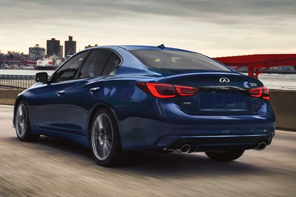 Rear profile of a grand blue 2021 INFINITI Q50 driving fast on the road.