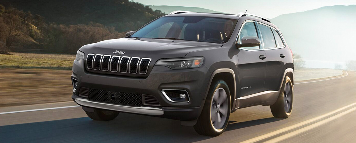 A 2021 Jeep Cherokee taking a left turn at a traffic light.