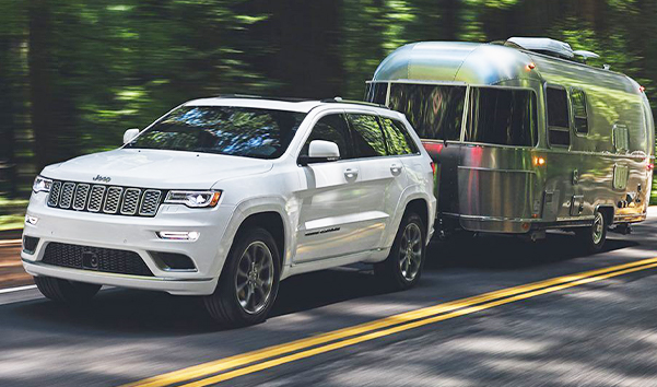 The 2021 Jeep Grand Cherokee towing a travel trailer.