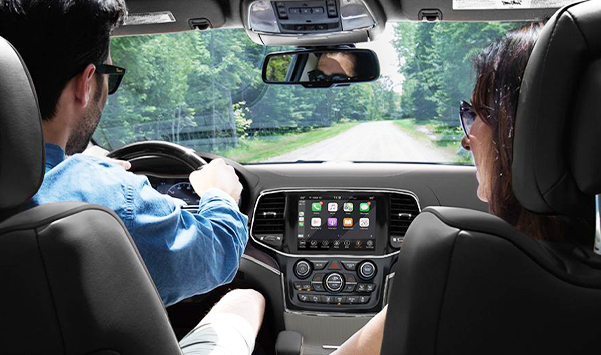 couple driving in 2021 Jeep Grand Cherokee with view of interior dashboard.