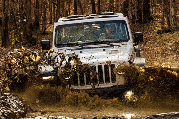 The 2021 Jeep Wrangler Rubicon being driven through a muddy stream.