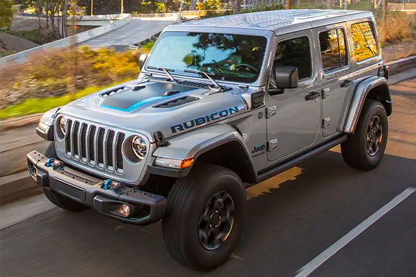 The 2021 Jeep Wrangler 4xe being driven on a street past skyscrapers.