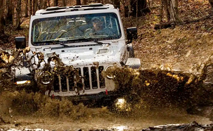 The 2021 Jeep Wrangler Rubicon being driven through a muddy stream.
