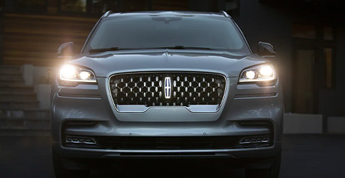 A 2021 Lincoln Aviator is shown with features included in the Illumination Package lit up including the Lincoln Star logo in the center of the grille