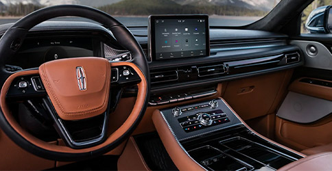 The steering wheel of a 2021 Lincoln Aviator is featured with snow capped mountains shown through the windshield