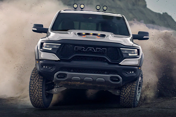 Display A 2021 Ram 1500 TRX being driven toward the camera with a cloud of dust behind it.