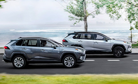 side profile of 2 2021 toyota rav4 hybrid accelerating down the road near a beach