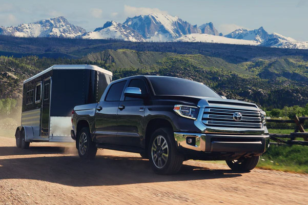 black Toyota Tundra showcasing towing capabilities on a dirt road with snow mountains in the background  