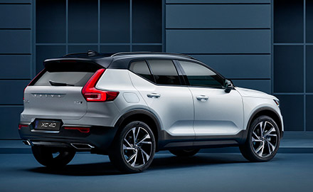 A Volvo XC40 stands parked along a blue facade