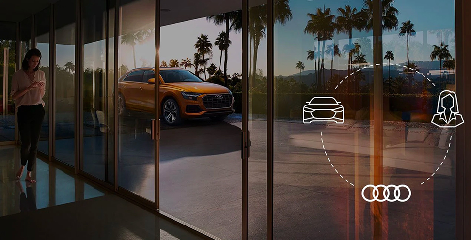 View of Audi model parked in driveway and owner using the Audi connect® feature.