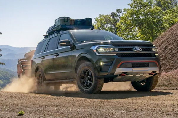 2022 Ford Expedition Timberline in Forged Green Metallic pulling a trailer on a dirt road