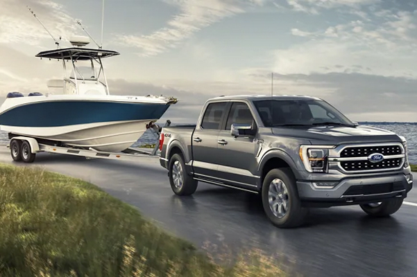 A 2022 Ford F-150 towing a boat on a road next to a lake