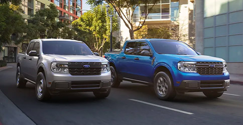 Two Ford Maverick trucks drive down a three-lane city street