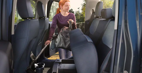 Woman putting bag into rear under-seat storage bins inside a 2022 Ford Maverick truck