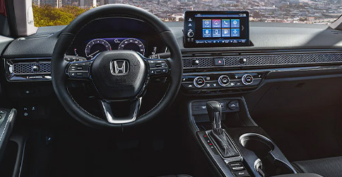 Interior view of the 2022 Honda Civic Touring Sedan with Black Leather, with a city skyline visible through the windshield.