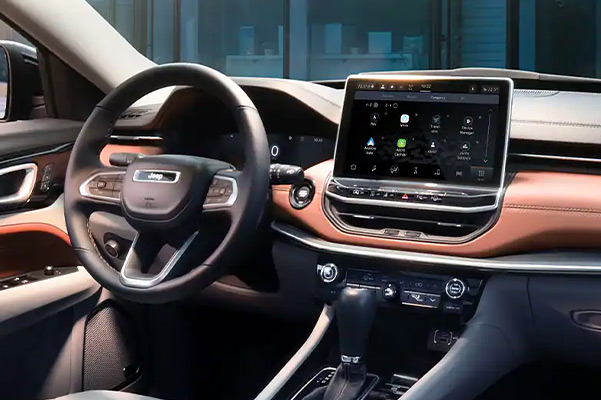 Close-up of the steering wheel, Uconnect touchscreen and center stack controls on the 2022 Jeep Compass.