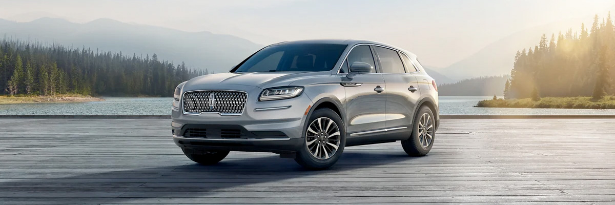 A 2022 Lincoln Nautilus Reserve in Silver Radiance is parked in front of a scenic landscape
