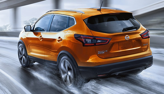 2022 Nissan Rogue Sport In Monarch Orange Metallic On Wet Highway In The City Illustrating All Wheel Drive