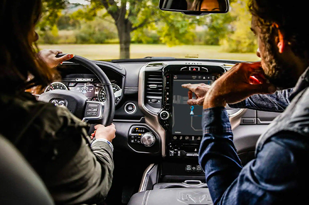 A driver and passenger in the 2022 Ram 2500 with the passenger gesturing to a map on the touchscreen.