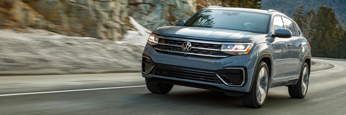 Atlas Cross Sport in Pure Gray drives down a two-lane mountain road, as seen from the front driver side