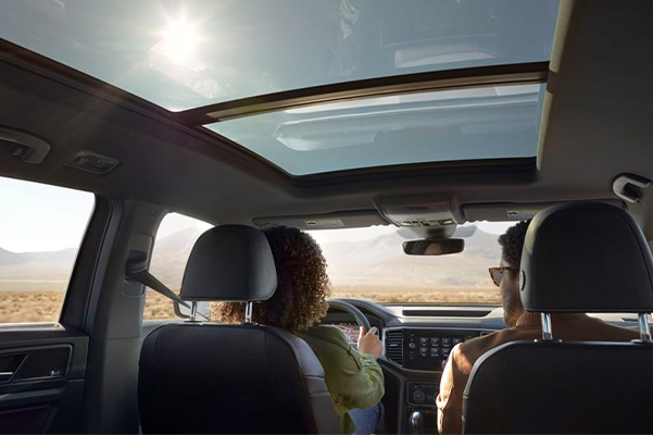 A driver and passenger inside the Atlas Cross Sport with the available panoramic sunroof.