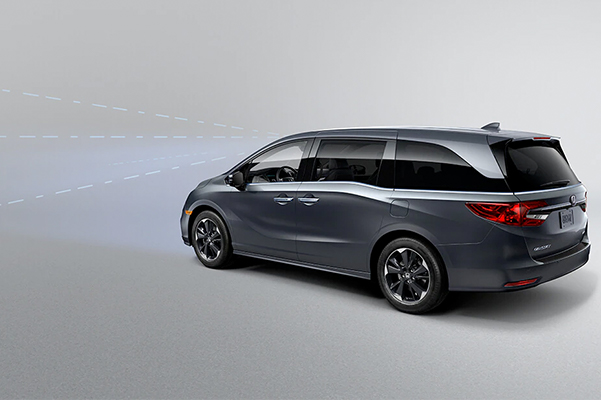 Rear driver-side view of the 2023 Honda Odyssey Elite in Modern Steel Metallic, demonstrating Collision Mitigation Braking System™ feature.