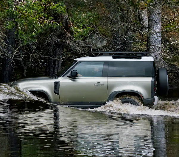 Side view of the 2023 Land Rover Defender 130 driving through water