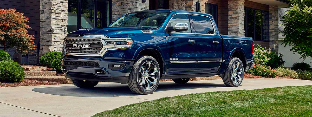 The 2023 Ram 1500 parked in the driveway of a large house.